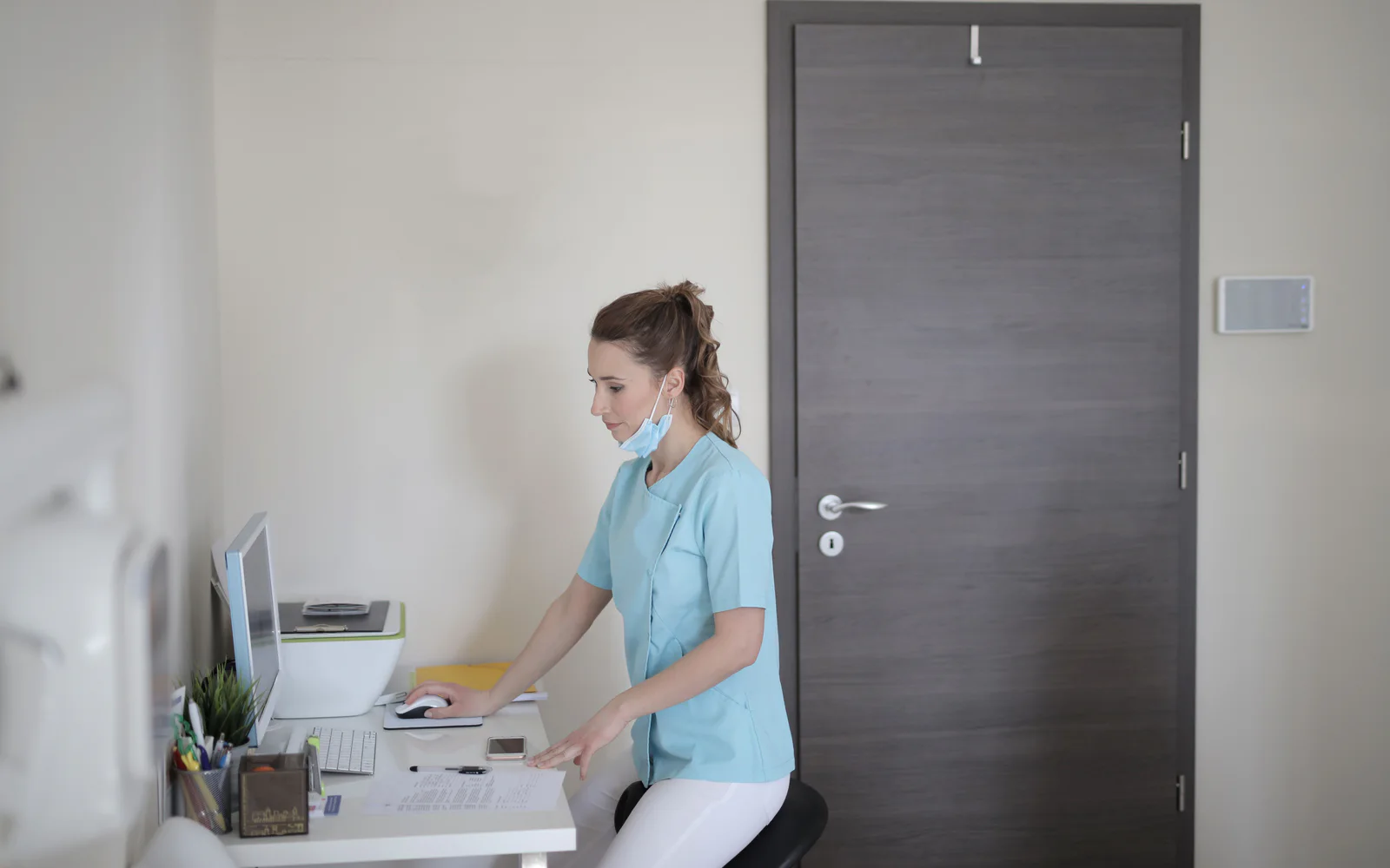 Healthcare professional using a computer at a desk in a modern clinic